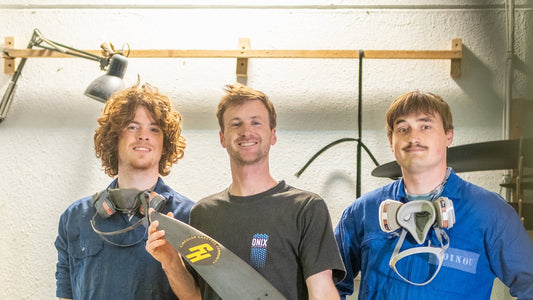 FoilHive team holding a carbon foil mast in the Tarifa workshop