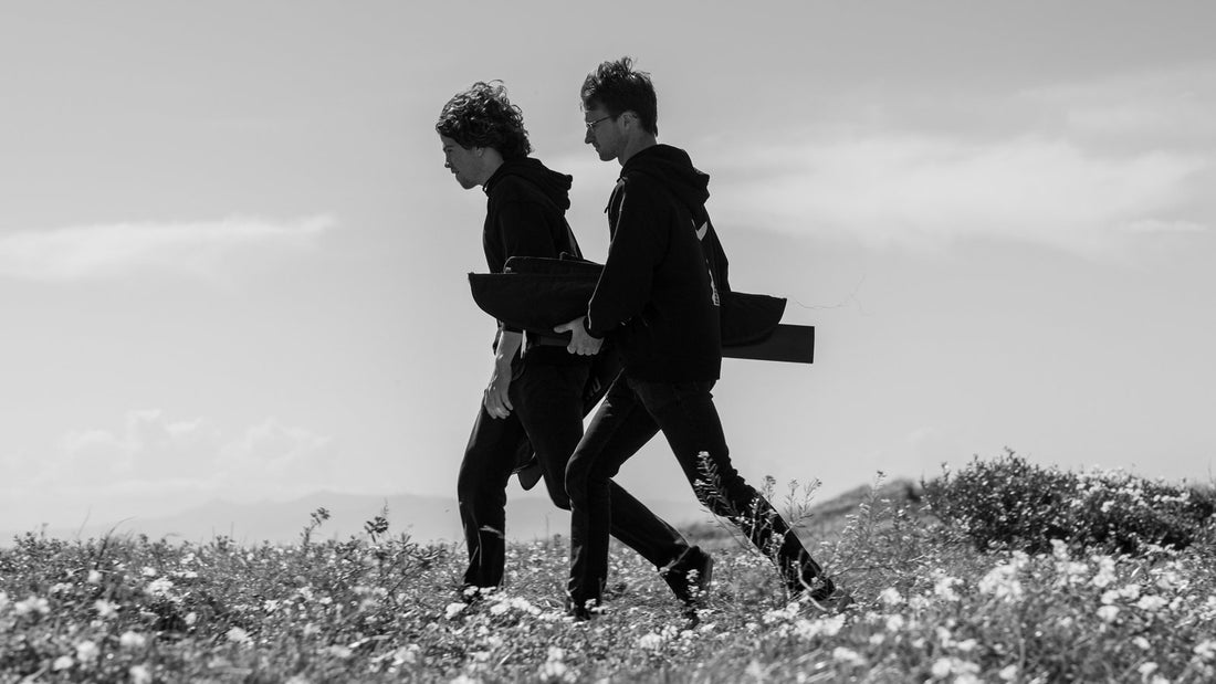 Two riders walking through wildflowers carrying a bagged foil