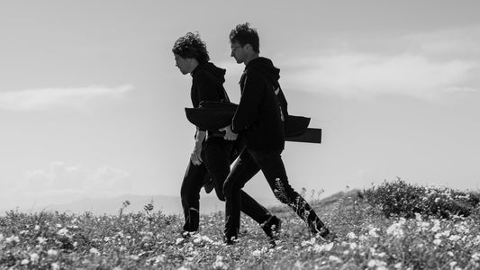 Two riders walking through wildflowers carrying a bagged foil