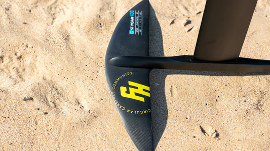 FoilHive carbon front wing on Tarifa sand with ocean horizon