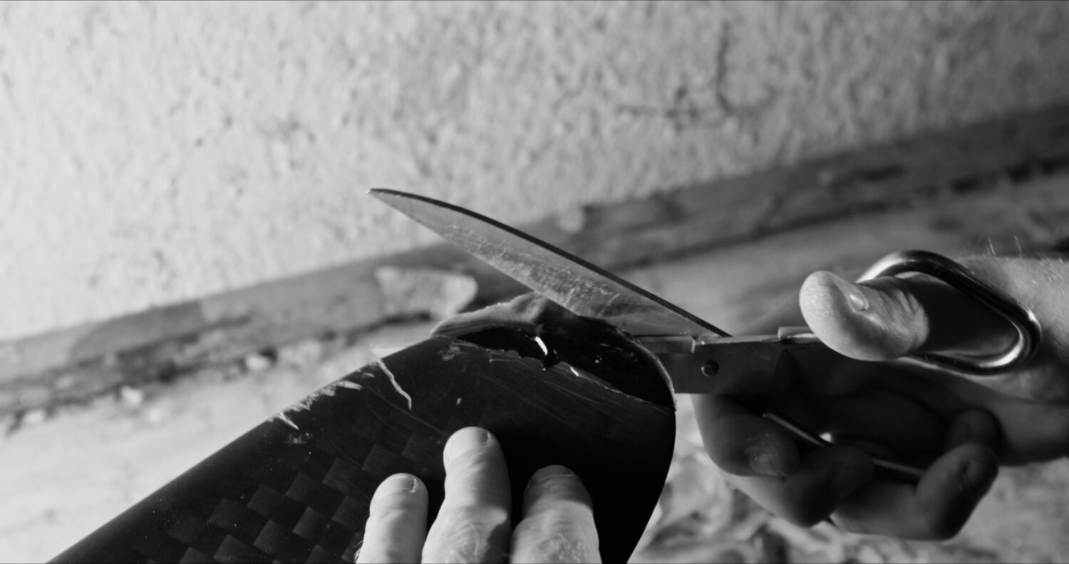 Hands repairing a foil wing in the Tarifa workshop